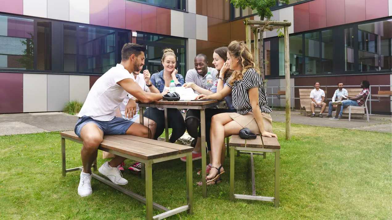 Estudiantes en una mesa de jardín en el campus de Rüsselsheim